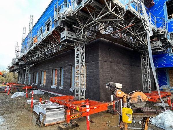 scaffoding above the first floor of a dark brick building under construction