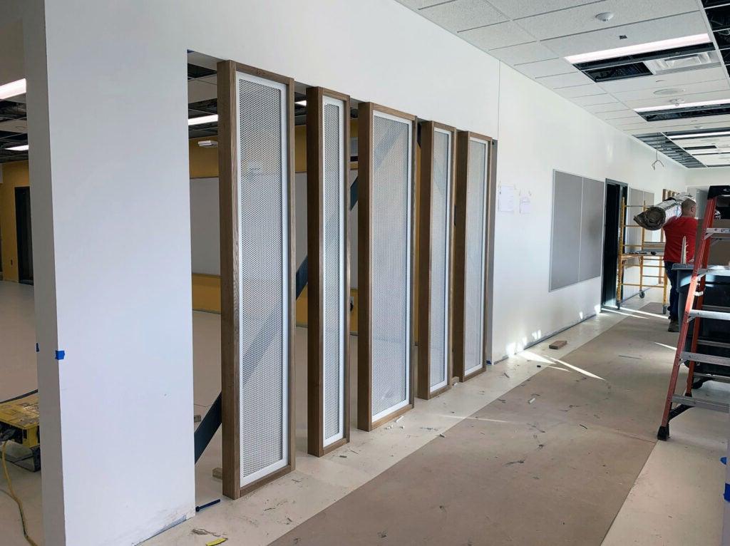 a hallway with a tackboard and framed screens separating it from another area