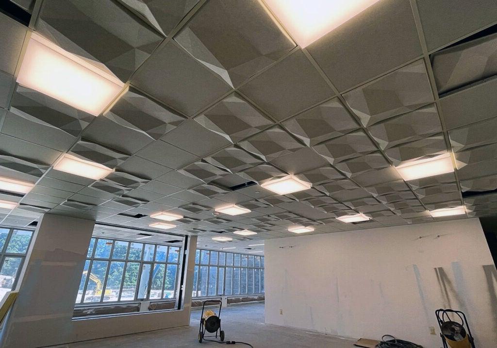 looking up to a ceiling with lights and dimensional ceiling tiles in a grid