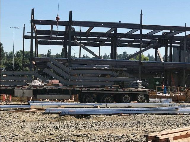 a steel frame has a large delivery trailer in front of it with bent steel on it