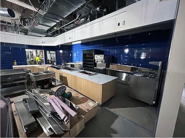 a large room with bright blue tile walls and metal kitchen equipment